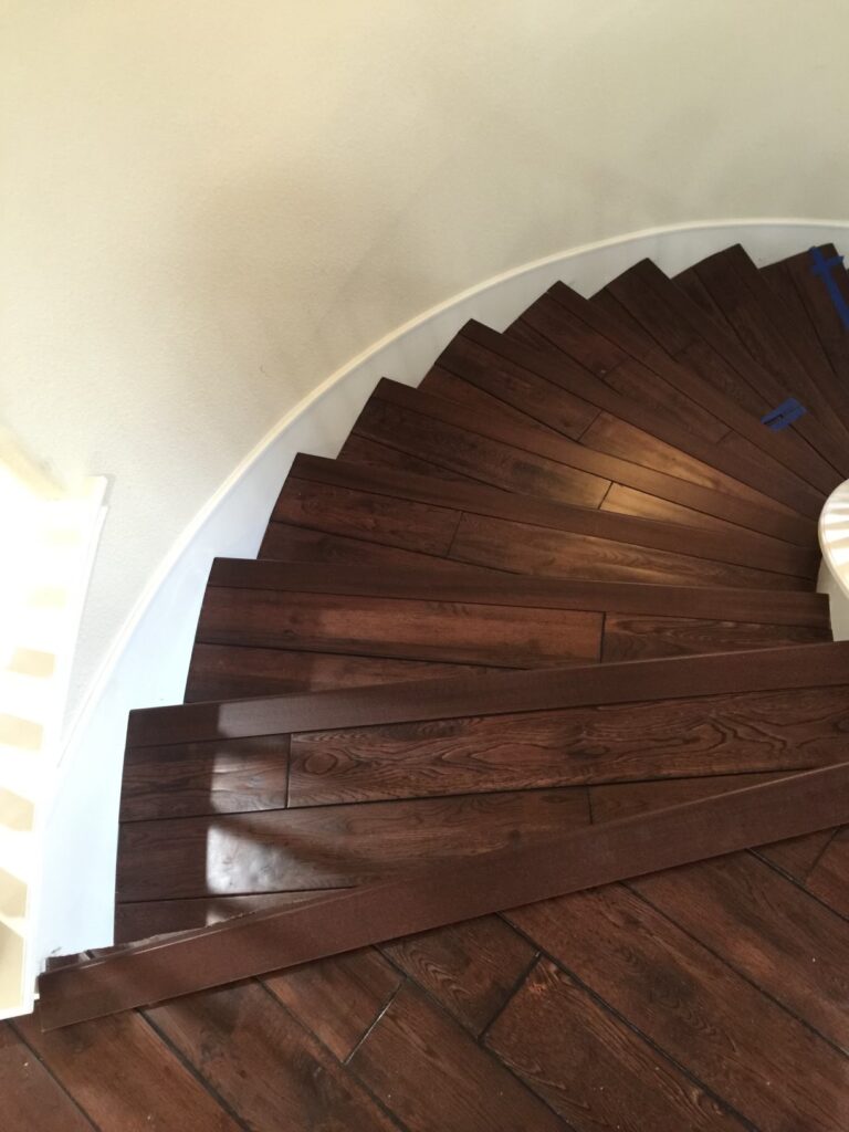 A wooden staircase with white walls and brown wood.