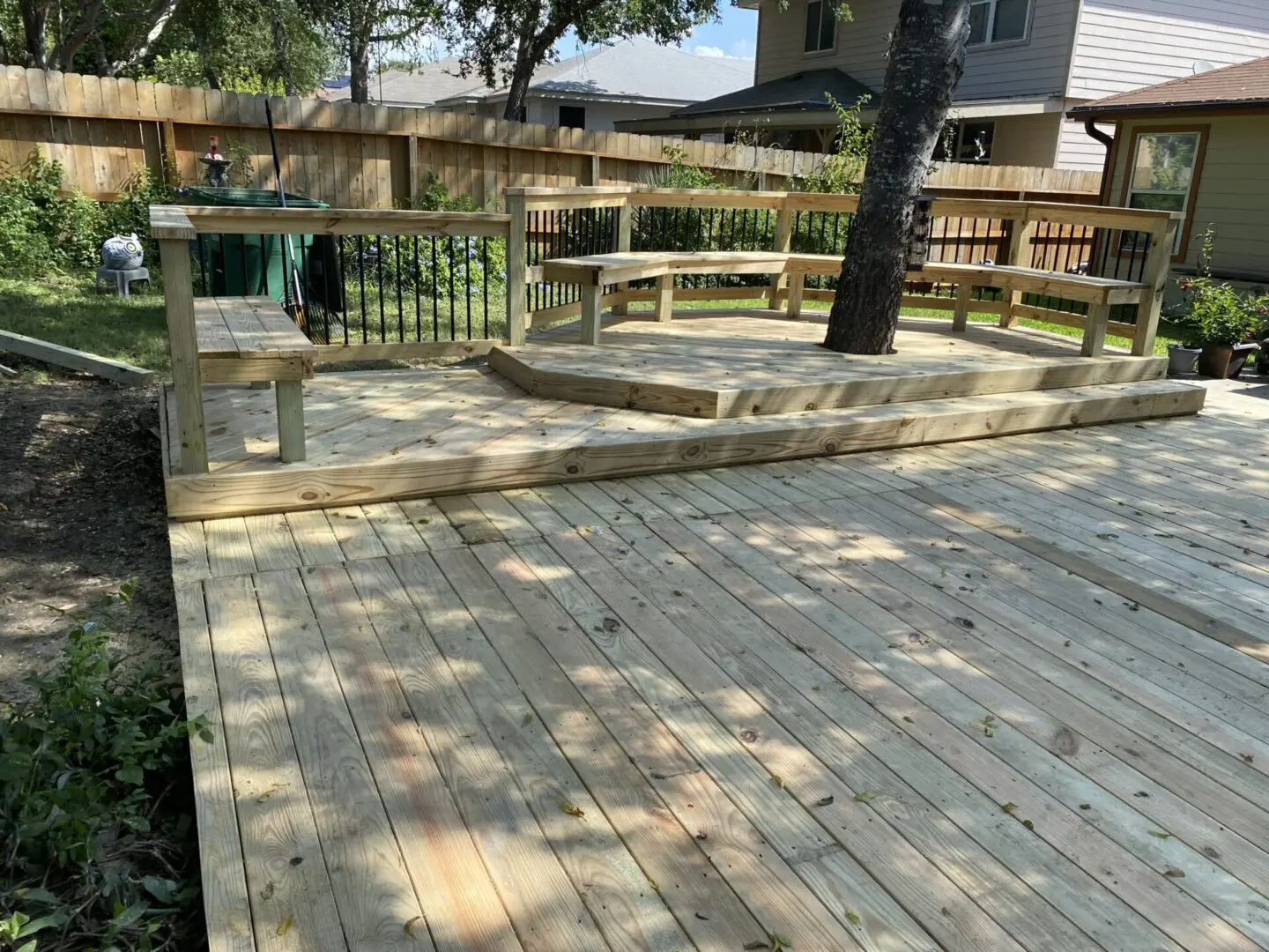 A wooden deck with benches and trees in the background.